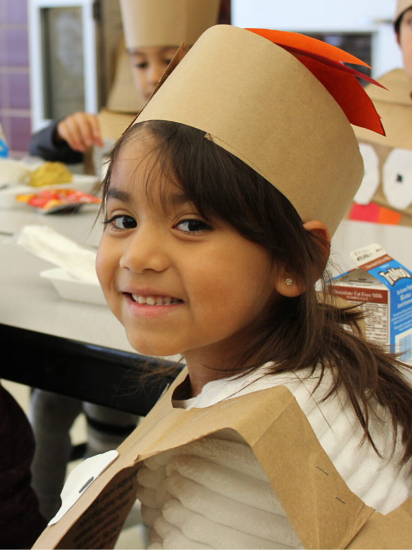 Student smiles and wears turkey headdress